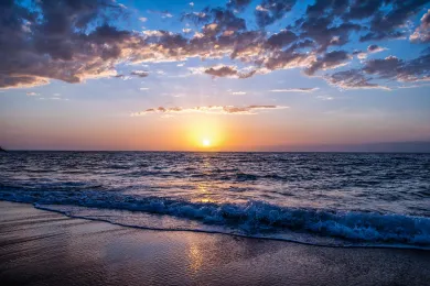 Sonnenuntergang am Strand mit dunklen Wolken.