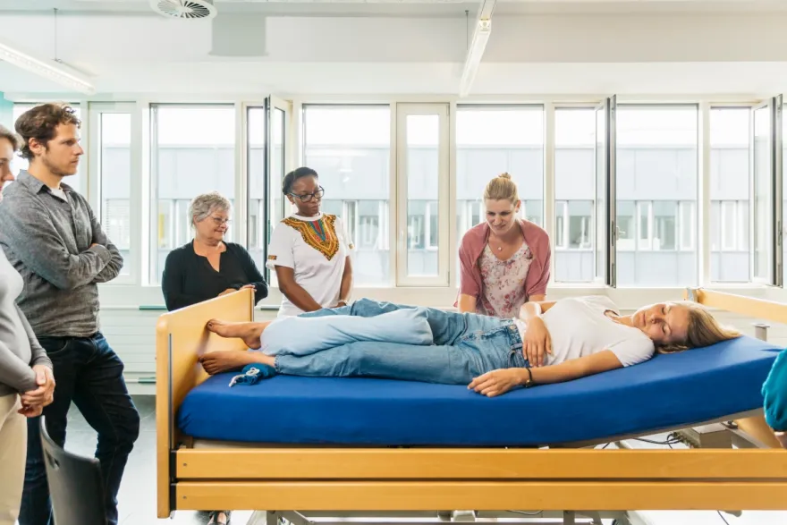 Klasse in der Weiterbildung zur Pflegehelfenden SRK steht um ein Pflegebett herum